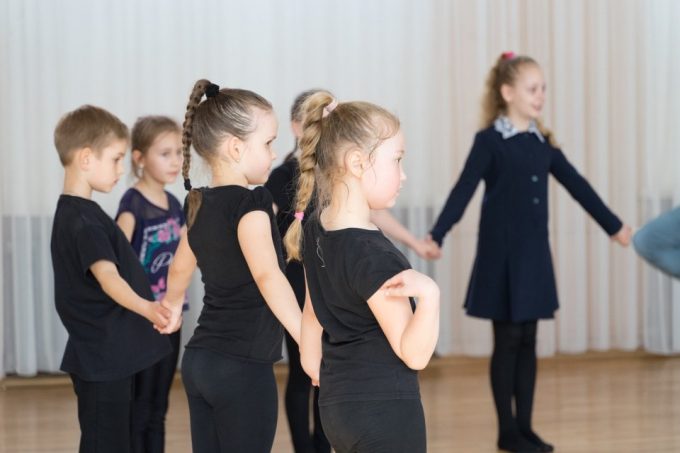 Young children hold hands during creative drama exercise.