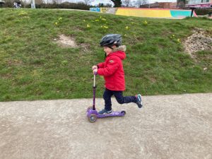 Small boy rides three wheeled scooter